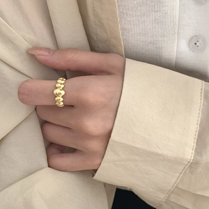 Gros plan d'une bague bulle en argent S925 dorée au doigt avec texture métallique douce