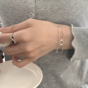 Detail of silver S925 snake chain bracelet with rings and black bow ring on model hand