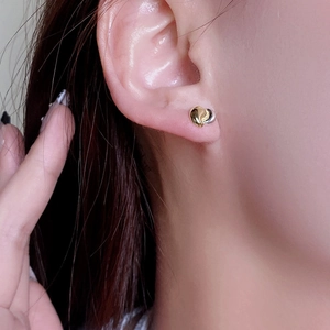 Macro close-up of two-tone 925 sterling silver heart studs worn on earlobe