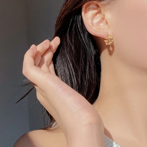 Close-up of golden S925 sterling silver chain-link oval earrings worn on the ear