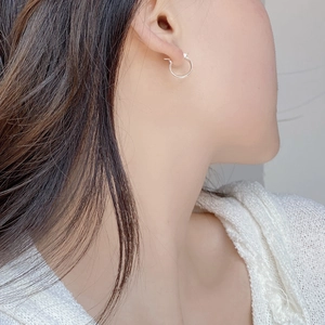 Primo piano di orecchini a cerchio in argento spazzolato su modella con luce morbida