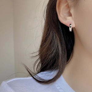 Dettaglio degli orecchini a cerchio a cuore in argento sterling su un orecchio