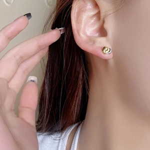 Macro shot of two-tone 925 sterling silver heart studs on ear for size comparison