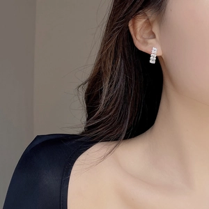 Macro detail of rectangular zircon earrings set in sterling silver on model ear