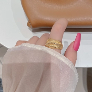 Macro detail of golden wave textured S925 silver ring worn on finger with leather bag