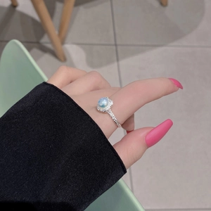 Detail of S925 silver ring with lava texture and iridescent blue moonstone on finger