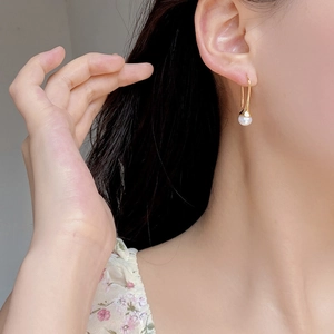 Close-up of elegant S925 silver gold-plated hook earring with a round white pearl