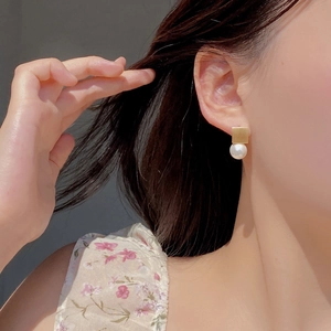 Close-up of vintage gold square stud earrings with white pearls on a female model