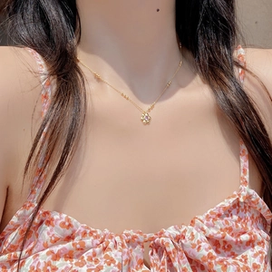 Model wearing gold flower necklace with pink crystal and delicate beaded chain detail
