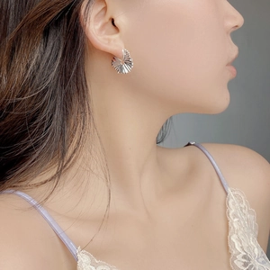 Macro detail of silver S925 pleated hoop earring shown on model with artistic texture