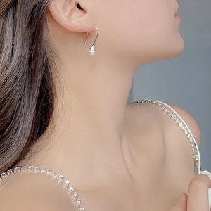 Close-up of S925 sterling silver curved hook earrings with white natural pearls on model