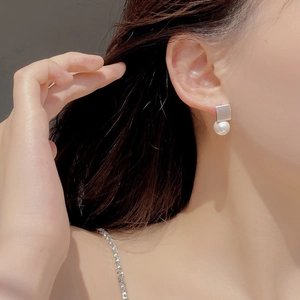 Macro shot of French vintage square matte silver stud earrings with round white pearls