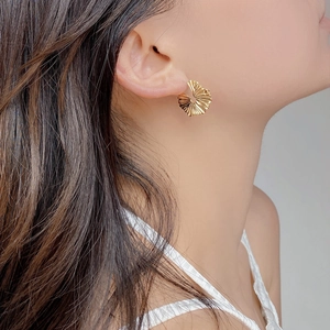 Close-up of pleated texture golden round earrings showing exquisite radial pattern