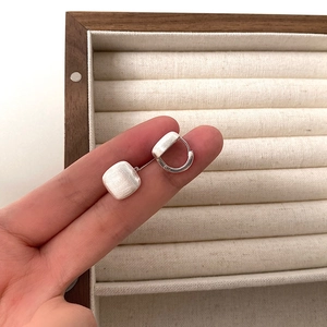 Macro shot of matte brushed S925 sterling silver square earrings on wooden box