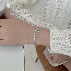 Detail of silver beaded bracelet with freshwater pearl and green gemstone on wrist