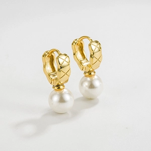 Macro view of gold diamond quilted earrings with round white pearl pendant details