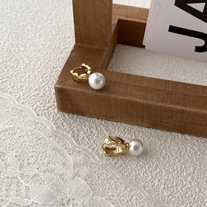 Detail of lattice engraved gold earrings with white pearls on a wooden frame