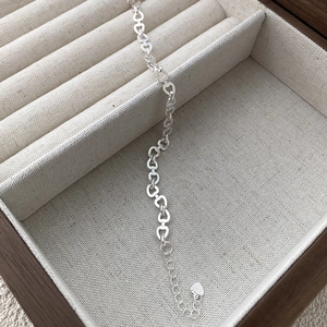 Macro detail of S925 sterling silver heart chain link bracelet on linen jewelry box