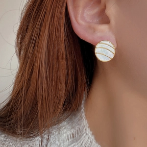 Detail of round S925 silver stud earring with white mother of pearl and gold finish
