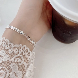 Macro detail of 925 sterling silver braided chain bracelet with heart charm on wrist