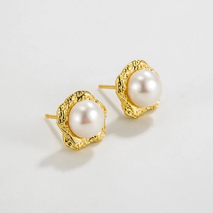 Close-up of irregular gold metal texture and white pearl on 925 silver stud earrings