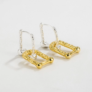 Détail de boucles d'oreilles en argent 925 avec pendentifs dorés à texture lave rectangulaire