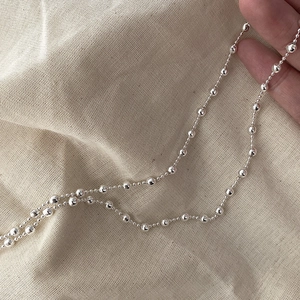 Detail of S925 sterling silver beaded necklace with mirror finish on linen background