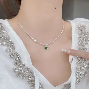 Detail of S925 silver necklace with emerald zircon pendant and pearl on female neck