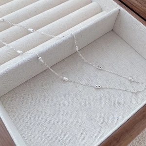 Macro detail of fine S925 sterling silver chain with small faceted cylinder beads