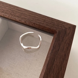 Macro-opname van een zilveren golvende open ring op een houten displaystandaard