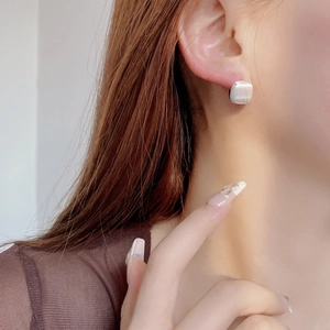 Detailed close-up of a square stud earring with a shimmering pearlescent cat-eye finish