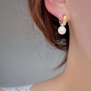 Close-up of quilted gold pearl earrings worn by model showing elegant vintage style