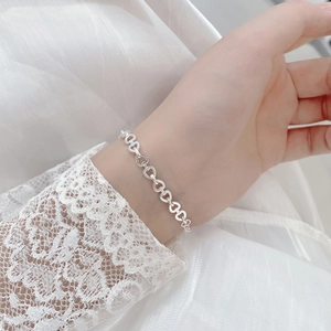 Close-up of S925 sterling silver bracelet featuring hollow heart-shaped links on model wrist