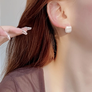 Close-up of minimalist matte square S925 silver stud earring worn on a model's ear