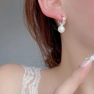 Quilted silver earrings with pearl pendants shown from a profile view on a model