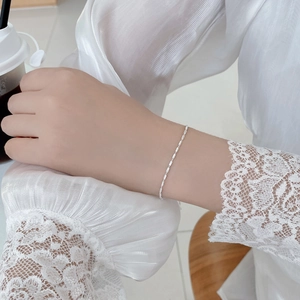 Macro detail of a minimalist S925 sterling silver chain bracelet on a lace sleeve wrist