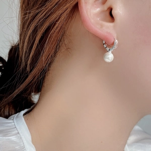Detailed close-up of a quilted silver pearl earring on model for elegant French retro style