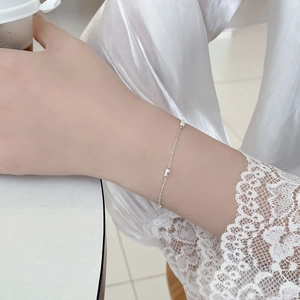 Gros plan d'un bracelet en argent S925 perlé sur poignet avec une manche en dentelle