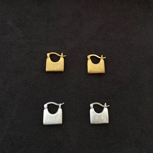 Detailed view of S925 sterling silver handbag earrings with a brushed matte finish