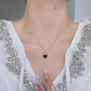 Close-up of a heart-shaped black onyx pendant with a delicate gold chain necklace