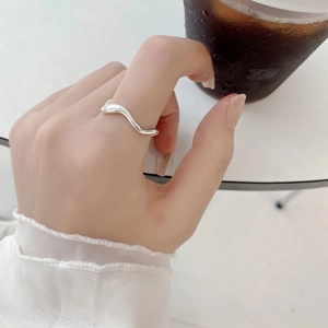 Close-up van een minimalistische zilveren golfring gedragen aan de wijsvinger in lifestyle