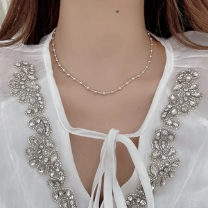 Close-up of minimalist S925 sterling silver beaded necklace on a model wearing white lace