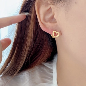 Close-up of a matte gold hollow heart earring worn on a model for a minimalist look