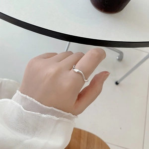 Detailopname van een minimalistische golfvormige ring van 925 sterling zilver om vinger