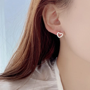 Close-up of S925 sterling silver hollow heart earrings worn by a model in soft lighting