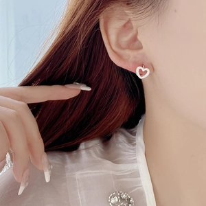 Elegant S925 sterling silver hollow heart hoop earrings worn by a model in soft light