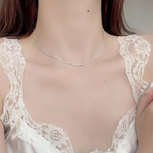 Close-up of a 925 sterling silver barrel chain worn on a woman's collarbone with lace