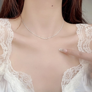 Close-up of a 925 sterling silver fine chain necklace worn on neck with white lace