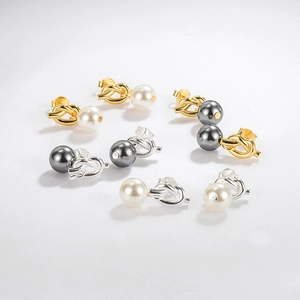 Detail of knot metal stud earrings with glass pearls in gold and silver finishes