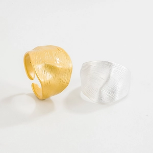 Detail of adjustable wide rings with unique wrinkled brushed texture in gold and silver